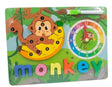 A colorful children's educational toy board featuring a monkey puzzle, a rainbow clock, and the word 'monkey' in movable letters, with a green marker at the top.